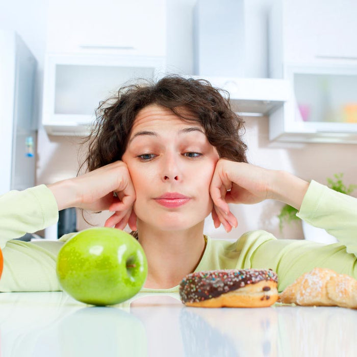 Woman choosing between an apple and a cupcake