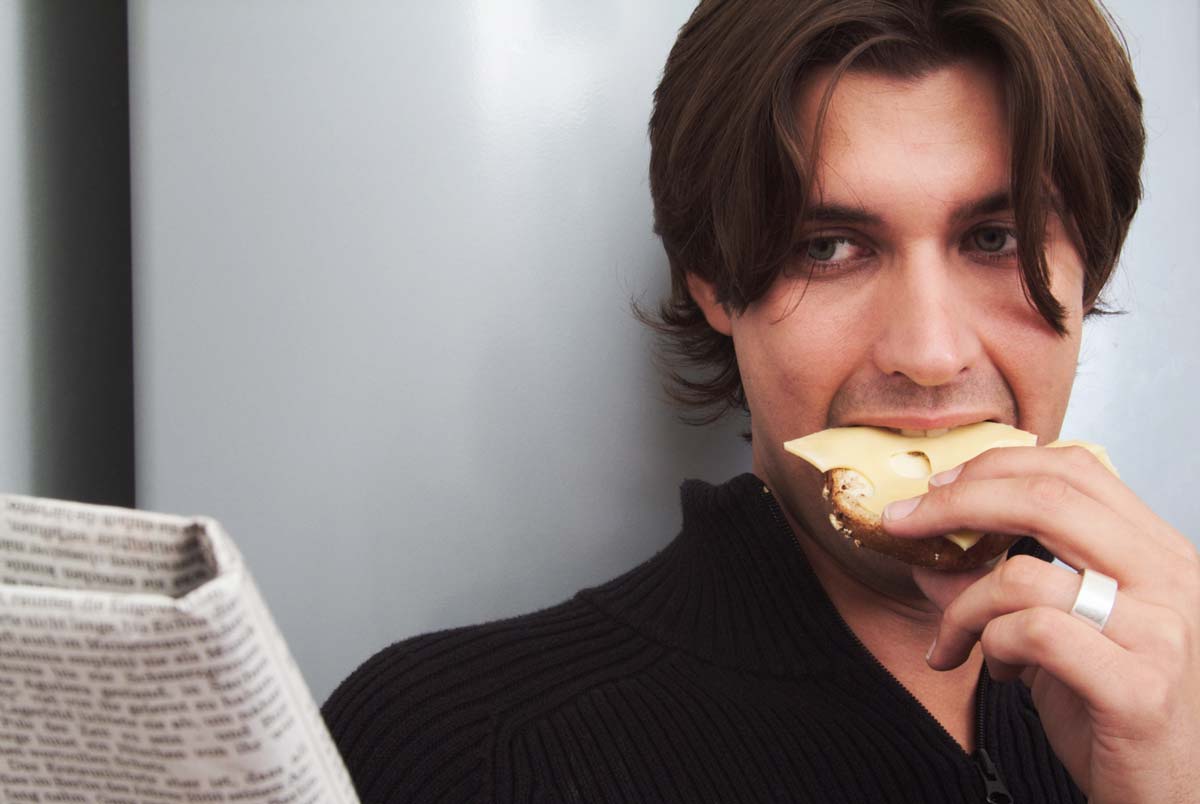Man eating toast while reading